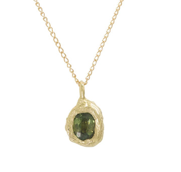 A hand carved 14k yellow gold rock embodies a natural Montana Sapphire and hangs on a 16
