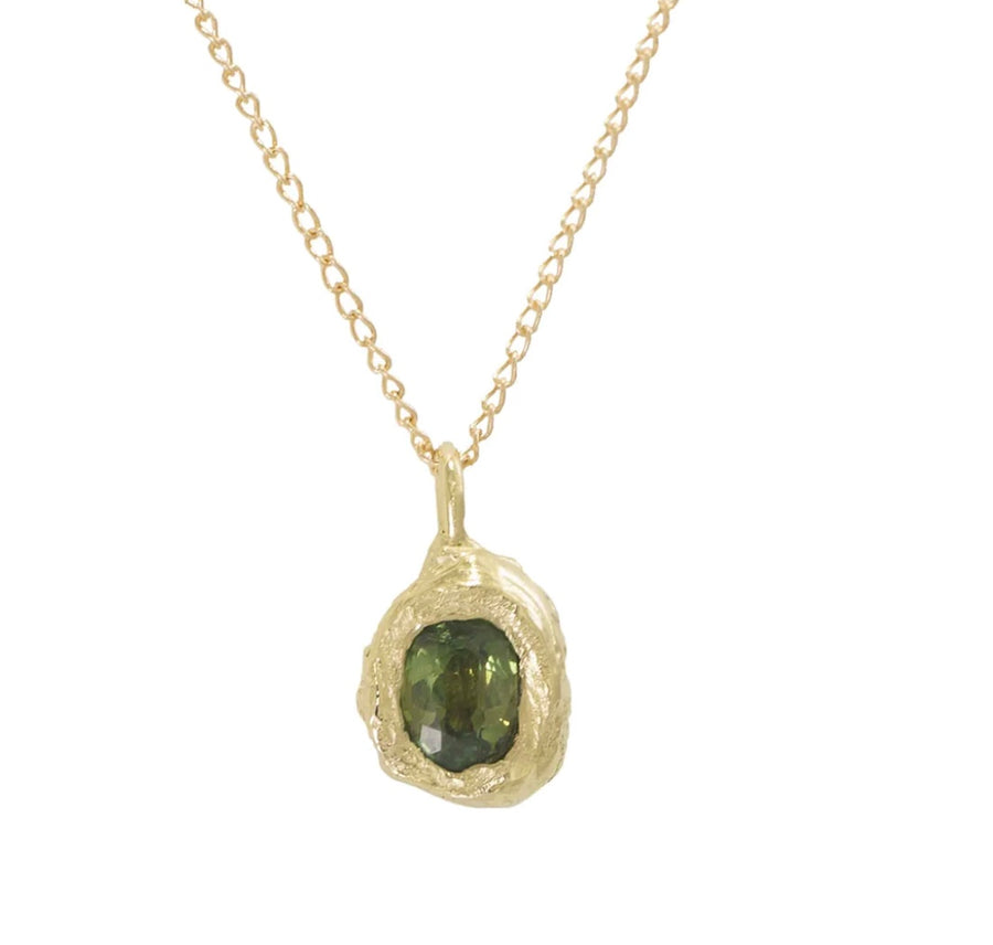 A hand carved 14k yellow gold rock embodies a natural Montana Sapphire and hangs on a 16