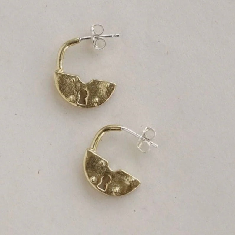 Like two open padlocks, these stud hoops are made of brass and sterling silver