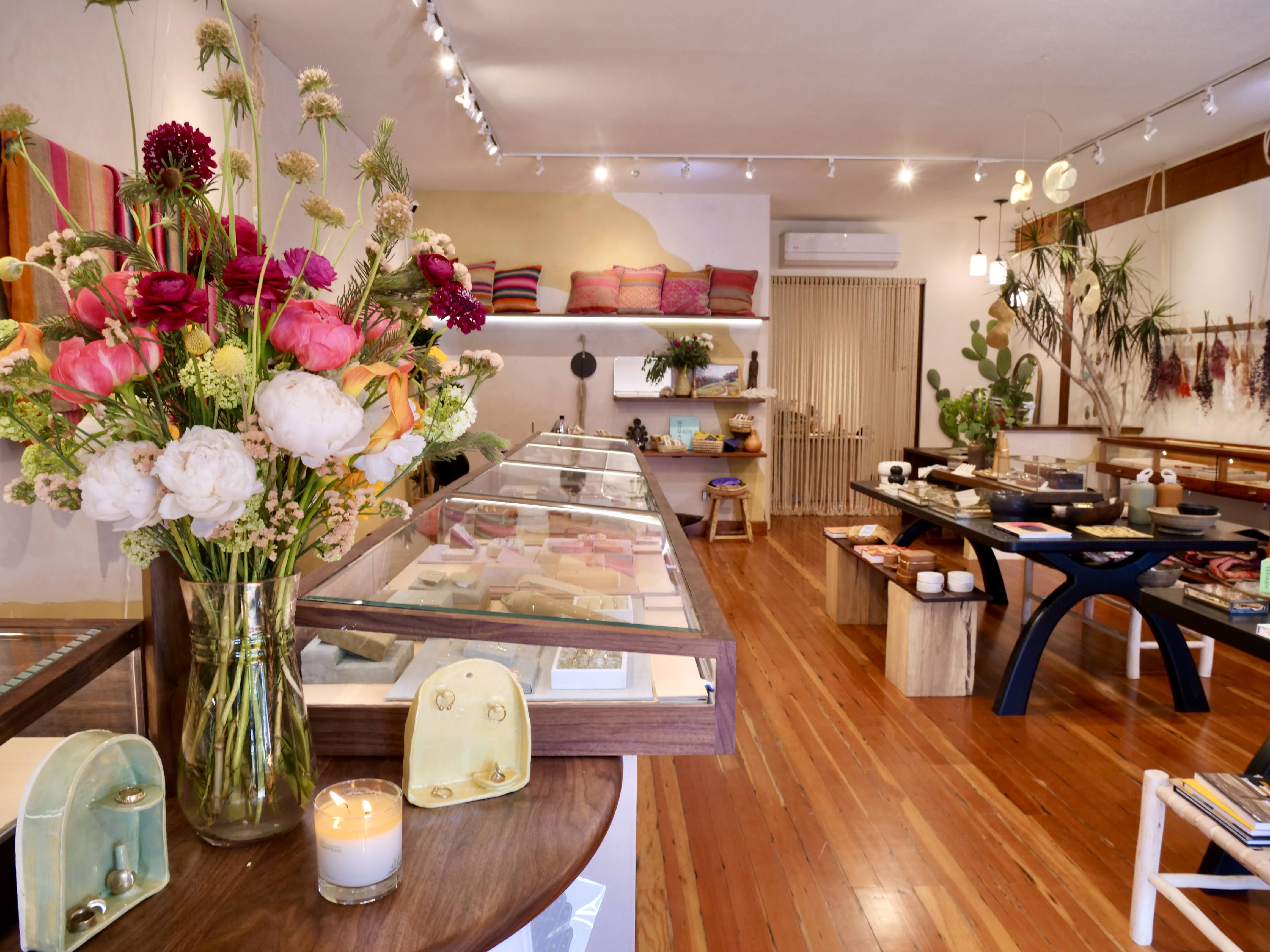 Interior of Berkeley store with jewelry case, flowers and candle, table with products 