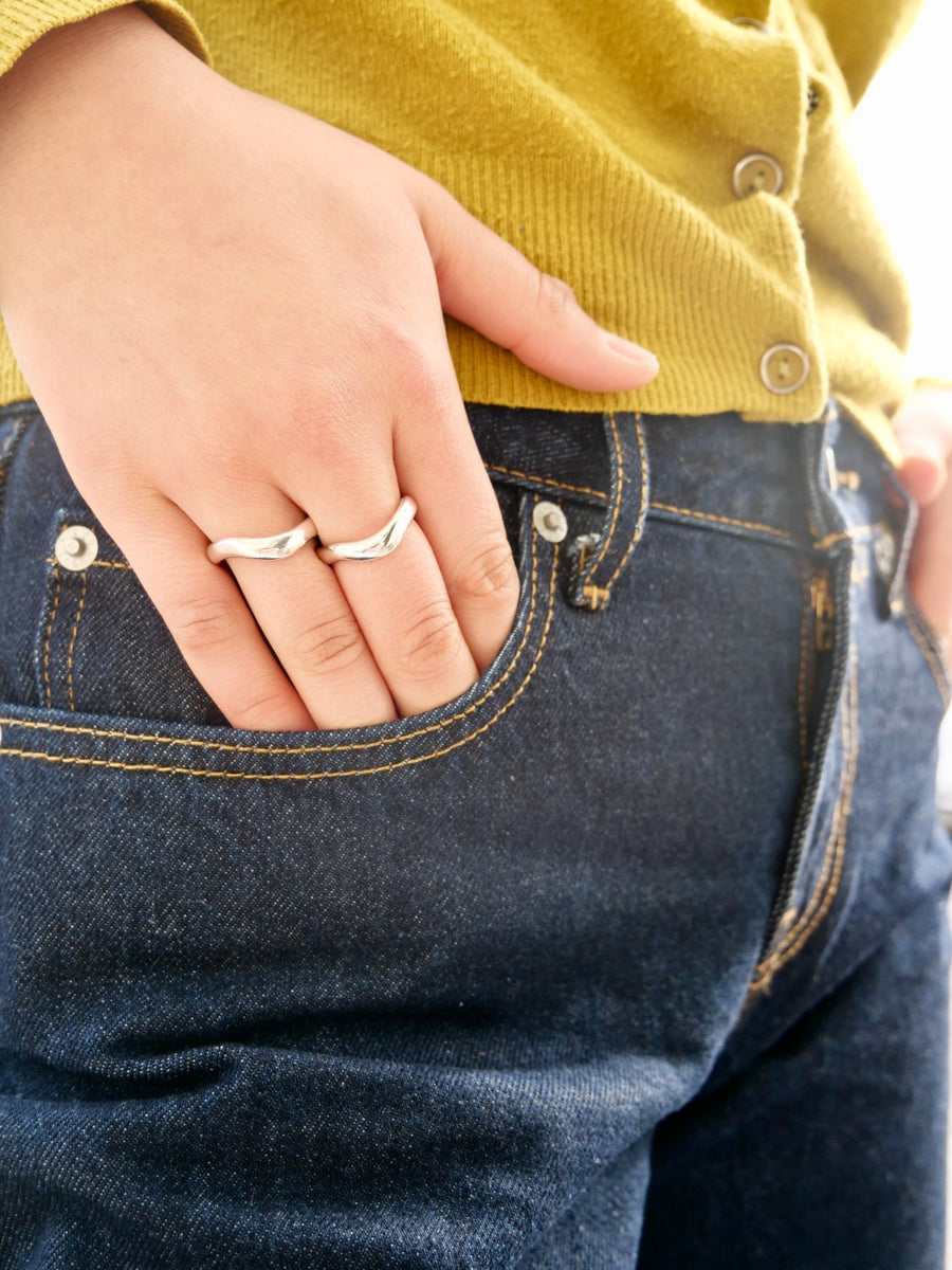 two wavy silver bands on hand in pocket