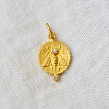 24k solid gold coin in bee embossed on one side and a deer embossed on the other, with two white diamonds