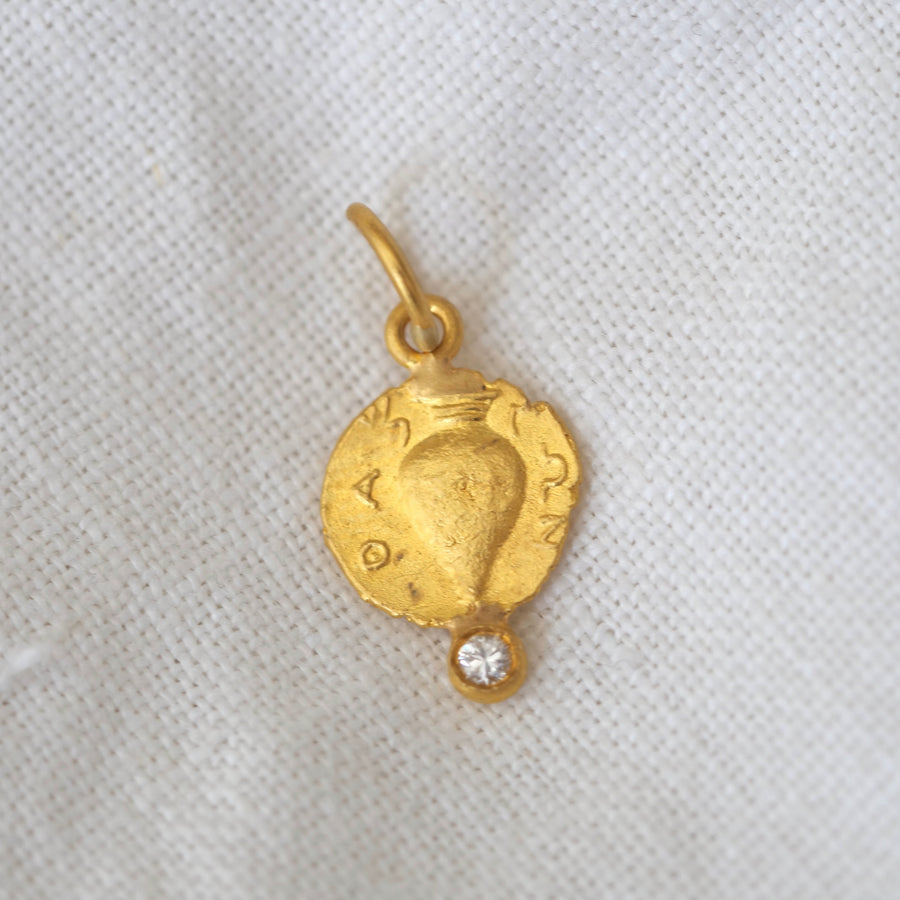 Amphora pendant. Crafted with rich 24K gold and adorned with a sparkling diamond, this ancient symbol of Dionysus exudes elegance and sophistication.