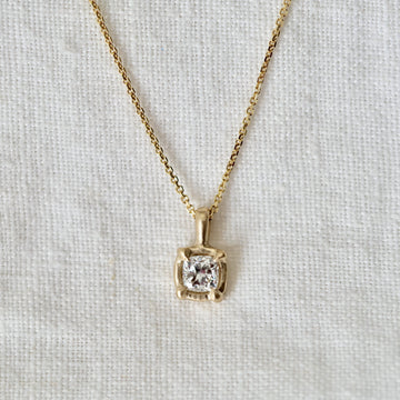 diamond set in 14K basket on a gold chain on white background 