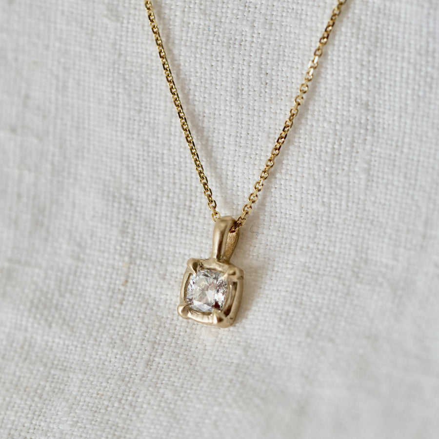 diamond set in 14K basket on a gold chain on white background 
