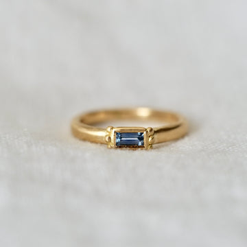 rectangular light blue sapphire solitaire stacking ring on white linen background
