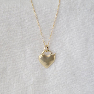 Gold heart-shaped pendant necklace on a light gray background