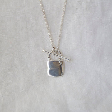Silver necklace with a pendant on a light gray background