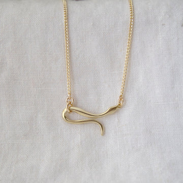 Gold snake-shaped pendant necklace on a light gray background