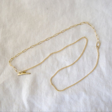 Gold chain necklace on a light beige fabric background