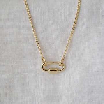Gold necklace with a unique clasp design on a light gray background