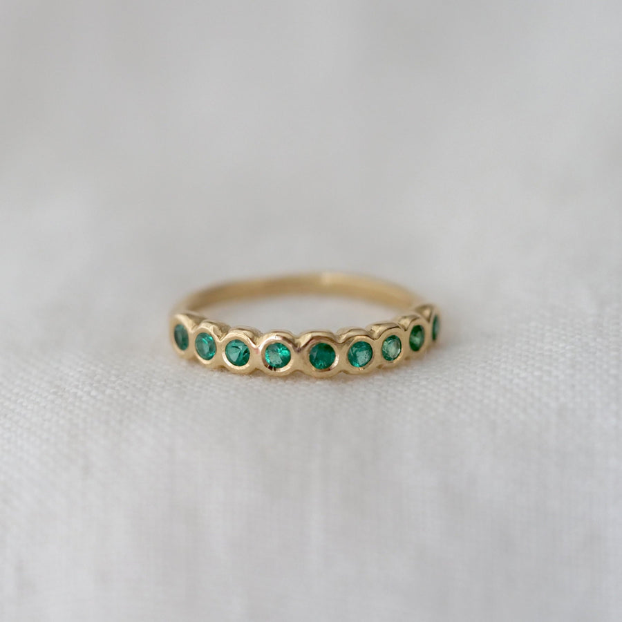Nine bright emeralds bezel set in a simple yellow gold band