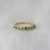 Nine bright emeralds bezel set in a simple yellow gold band