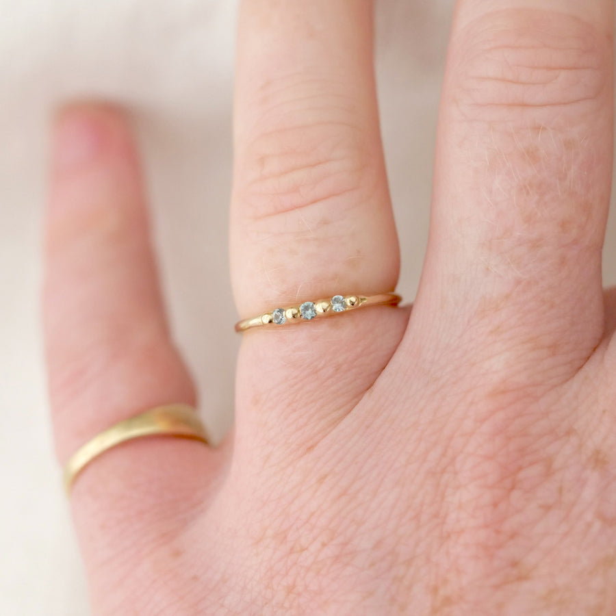 Close-up of a hand wearing two gold rings on a plain background
