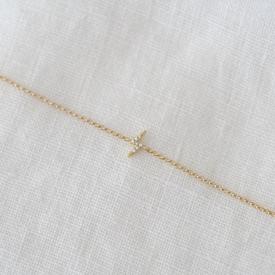 Gold necklace with a small pendant on a light fabric background
