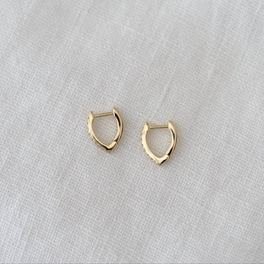 Gold hoop earrings on a light gray fabric background