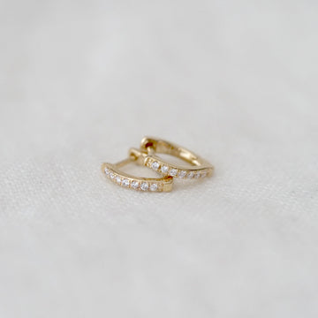 Two gold hoop earrings on a light gray background