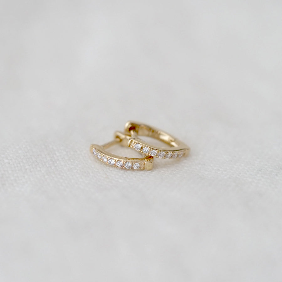 Two gold hoop earrings on a light gray background