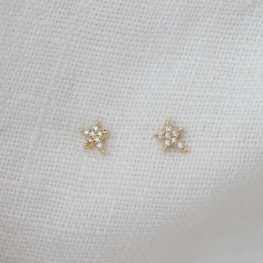 Pair of diamond star earrings on a light fabric background