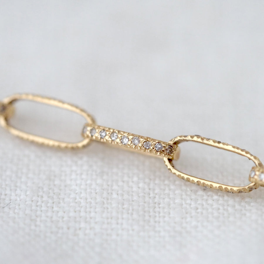 Gold bracelet with diamond accents on a light fabric background