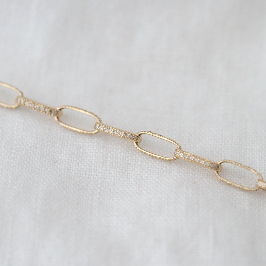 Gold chain bracelet on a light gray background