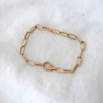 Gold chain bracelet on a white fabric background