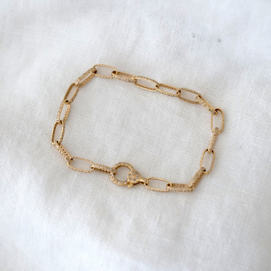 Gold chain bracelet on a white fabric background