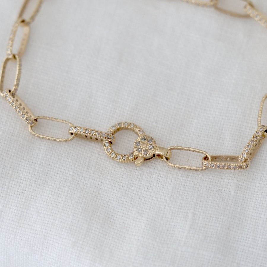Gold chain bracelet on a white fabric background