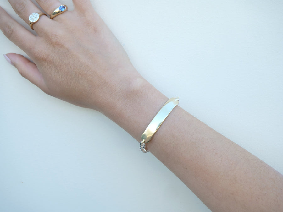 Hand wearing a gold bracelet on a light background