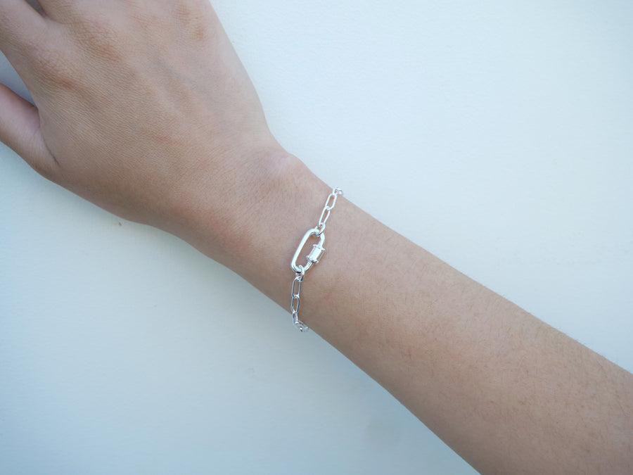 Silver bracelet on a wrist against a light background