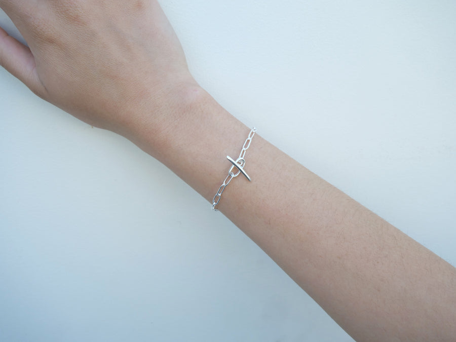 Silver bracelet on a wrist against a light background