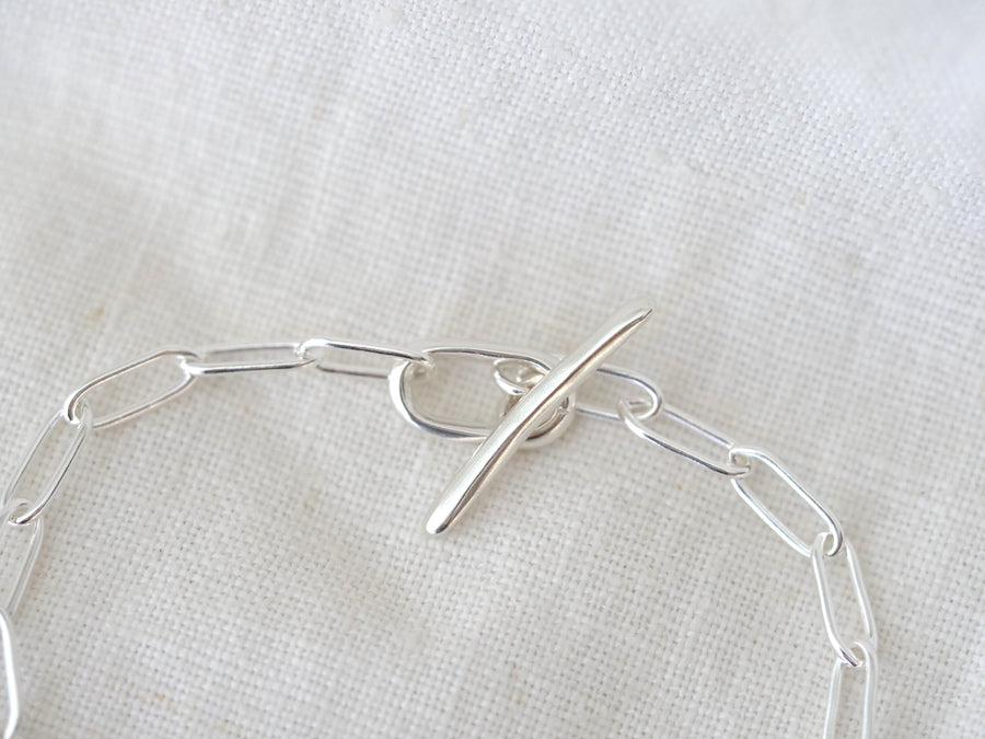Silver chain necklace on a textured white fabric background