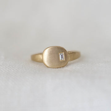 Gold ring with a small diamond on a white fabric background
