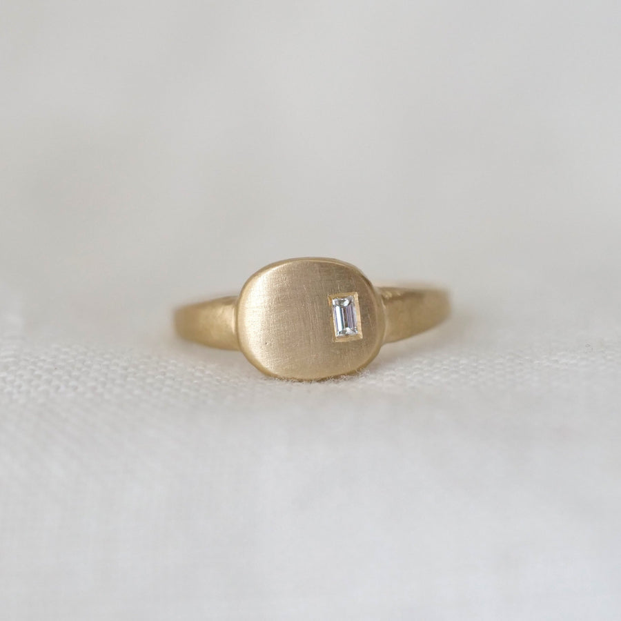 Gold ring with a small diamond on a white fabric background