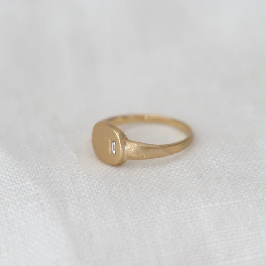 Gold ring with a diamond on a white fabric background