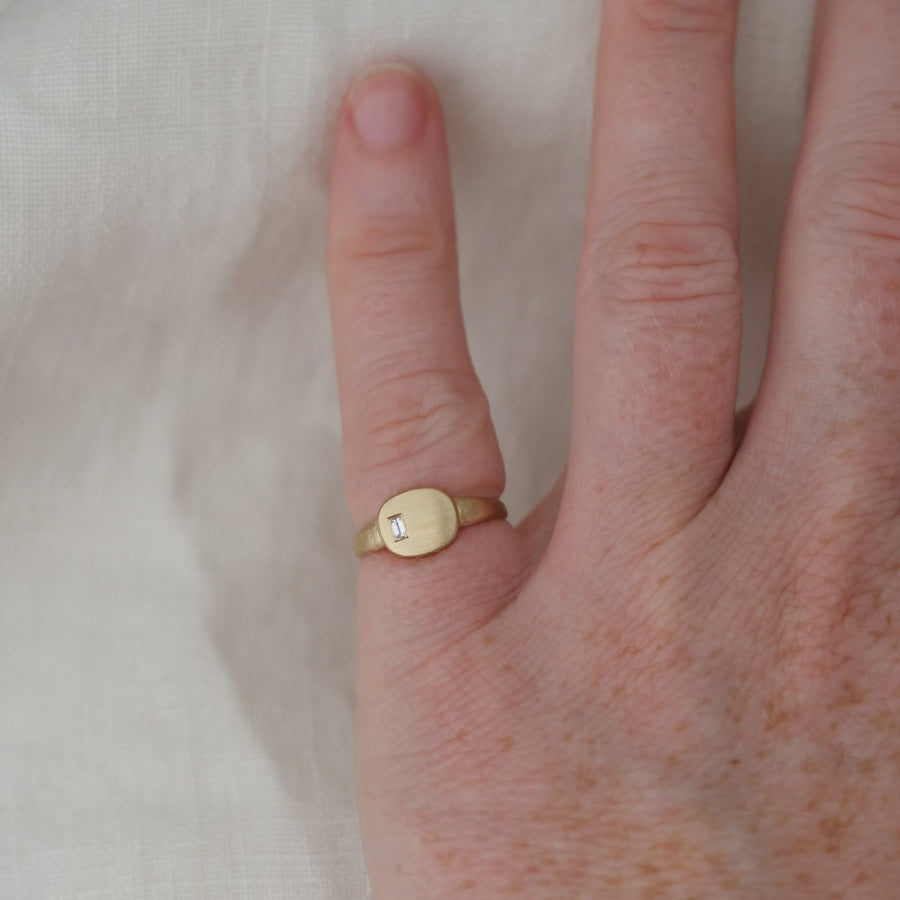 Gold ring with a diamond on a person's finger against a white background