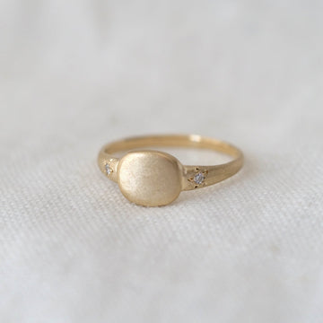 Gold ring with a star set diamond on a white fabric background