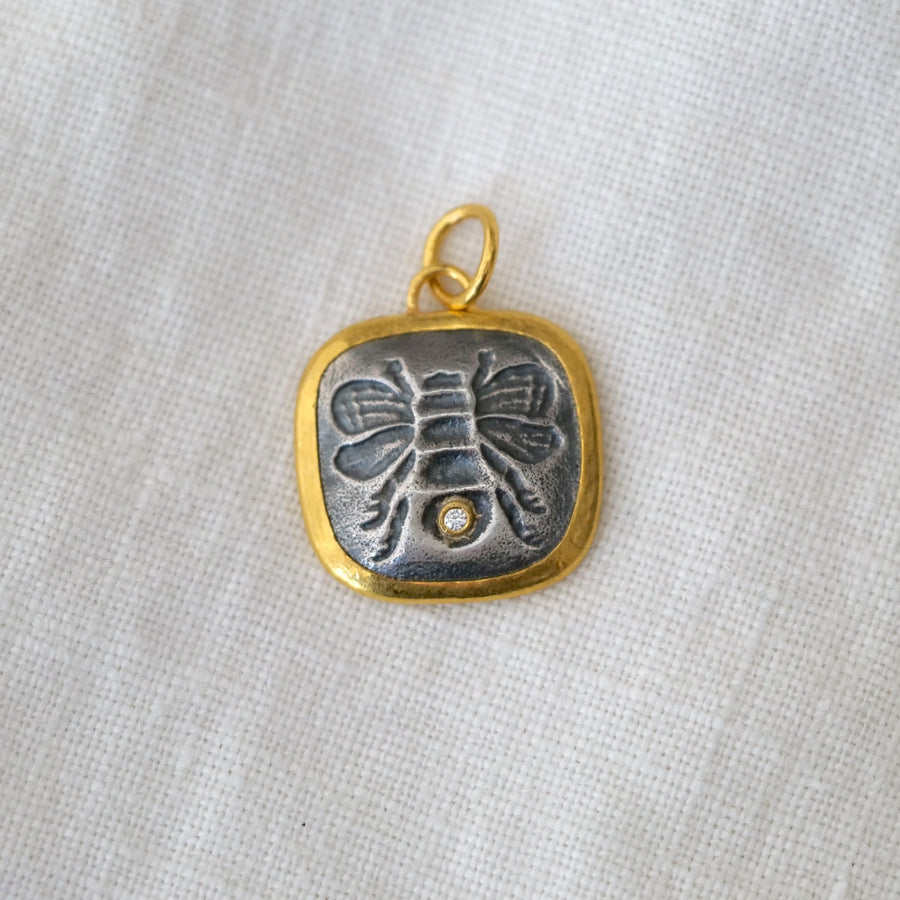 Silver and gold pendant on a light fabric background