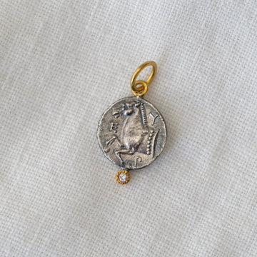 Silver pendant with gold chain on a light fabric background