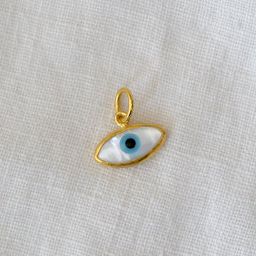 Gold pendant with an eye design on a light fabric background
