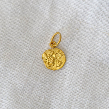 Gold pendant on a light gray fabric background