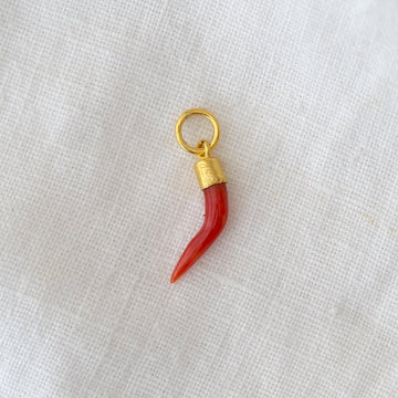 Red horn-shaped charm with gold base on a white fabric background