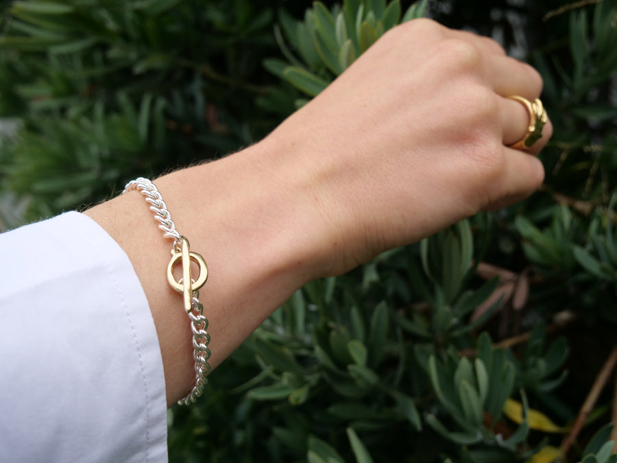 brass and silver bracelet on model in front of greenery