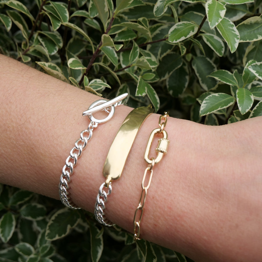 Three bracelets on a wrist with a green leafy background