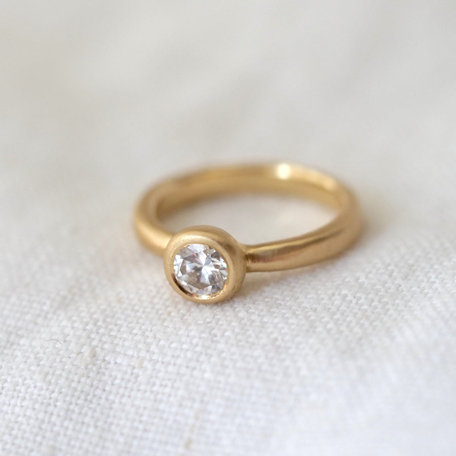 Gold ring with a diamond on a white fabric background