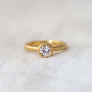 Gold ring with a diamond on a white fabric background