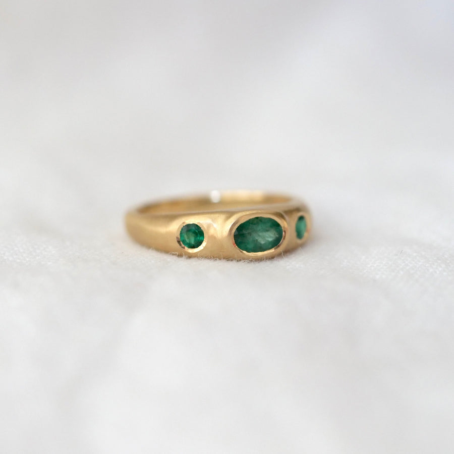 Gold ring with green gemstones on a white background