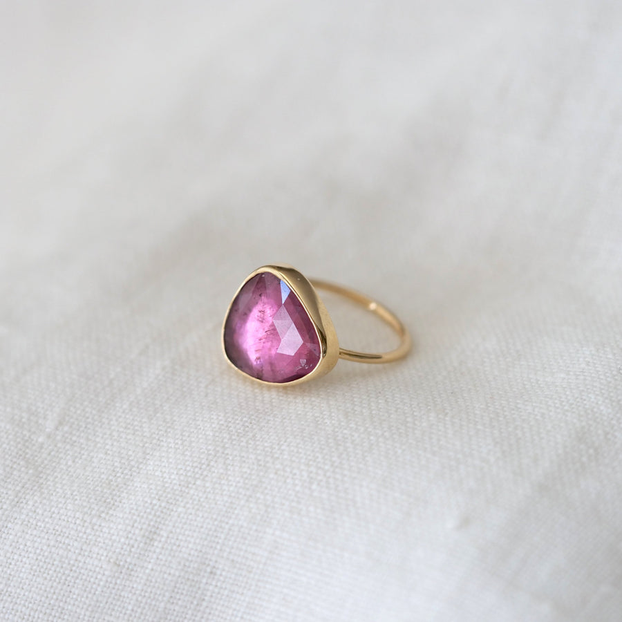 Gold ring with a pink gemstone on a white fabric background