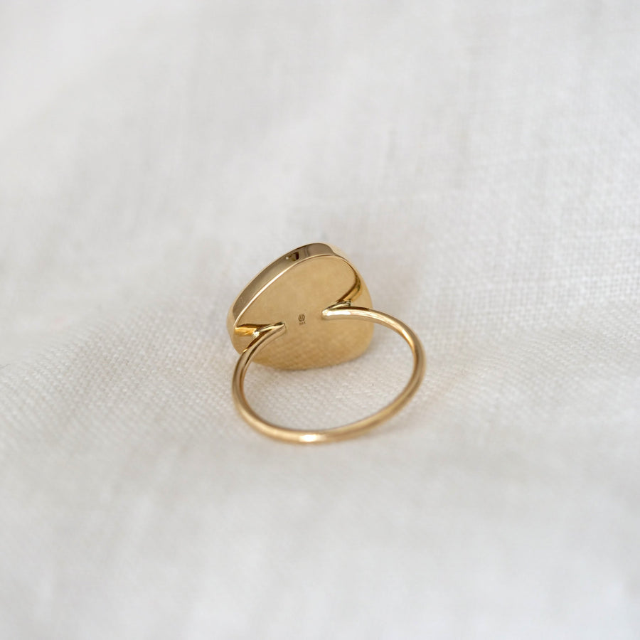 Gold ring with a unique design on a white fabric background