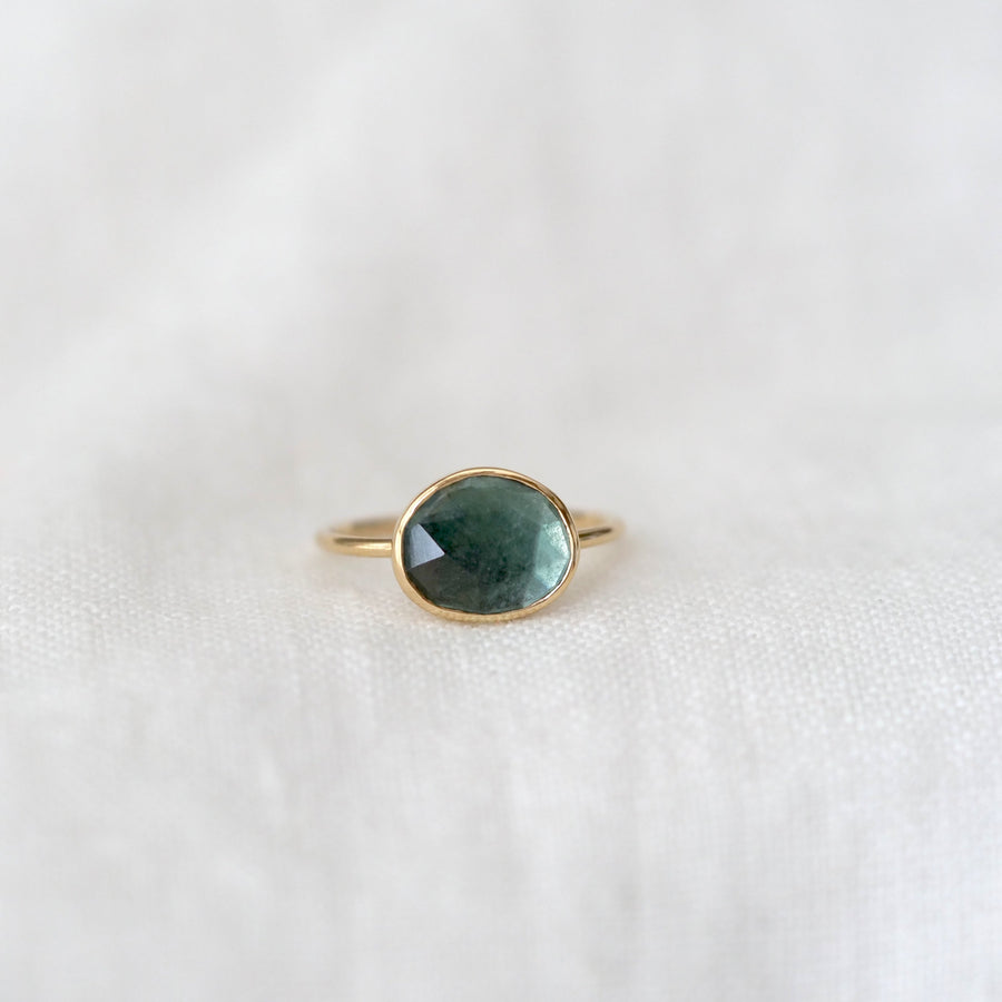 Gold ring with a green gemstone on a white background